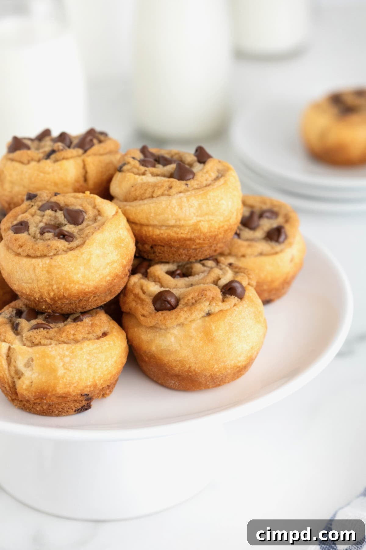 A large white plate stacked with chocolate chip cookie dough cruffins.