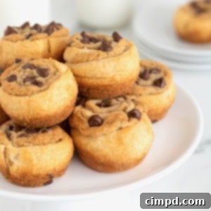 A large white plate stacked with chocolate chip cookie dough cruffins.