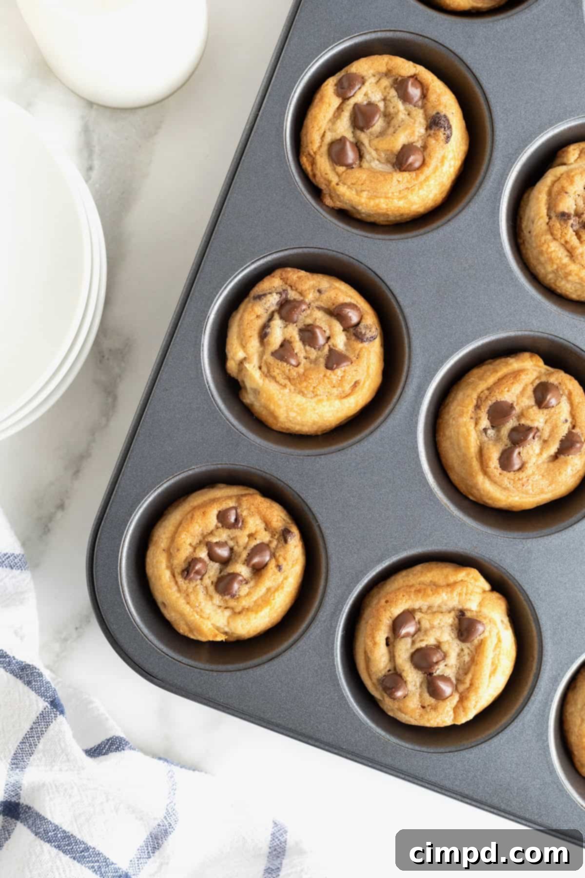Cruffins in a dark aluminum muffin pan on a white marble counter.