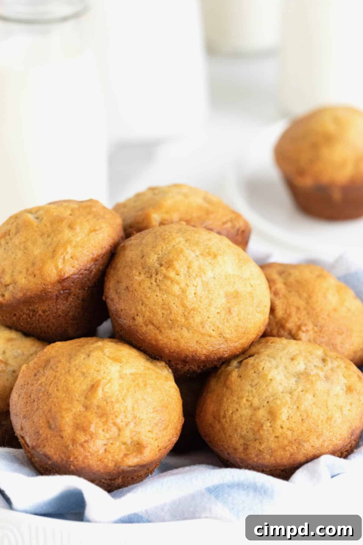 A large white bowl of freshly baked golden banana muffins, invitingly warm and ready to be enjoyed.