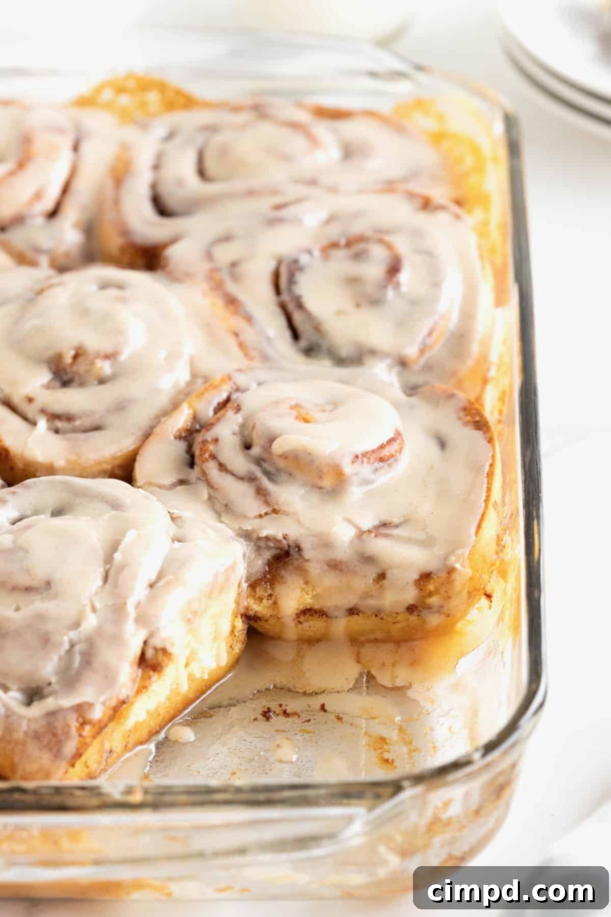 Store bought cinnamon rolls in a glass baking dish topped with icing.