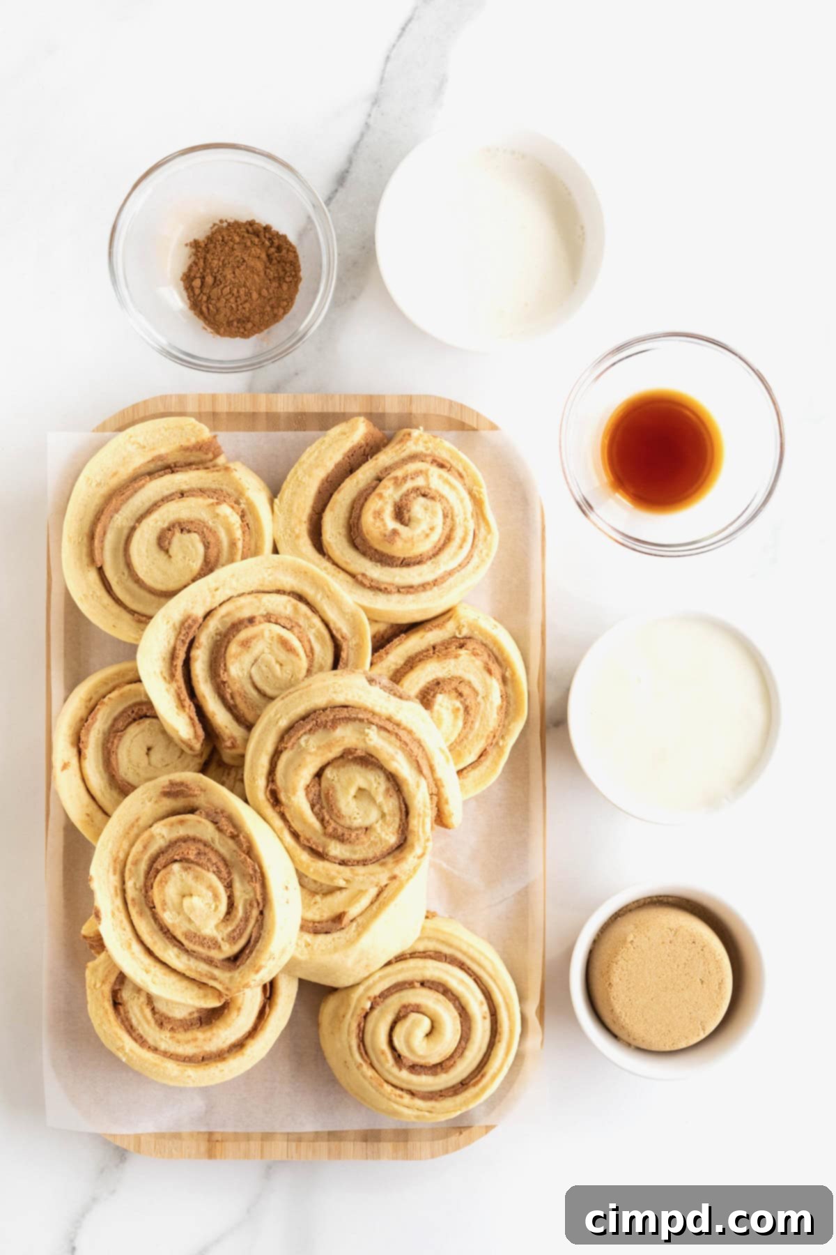 Ingredients to make the Canned Cinnamon Roll Hack in glass dishes on a white marble counter.