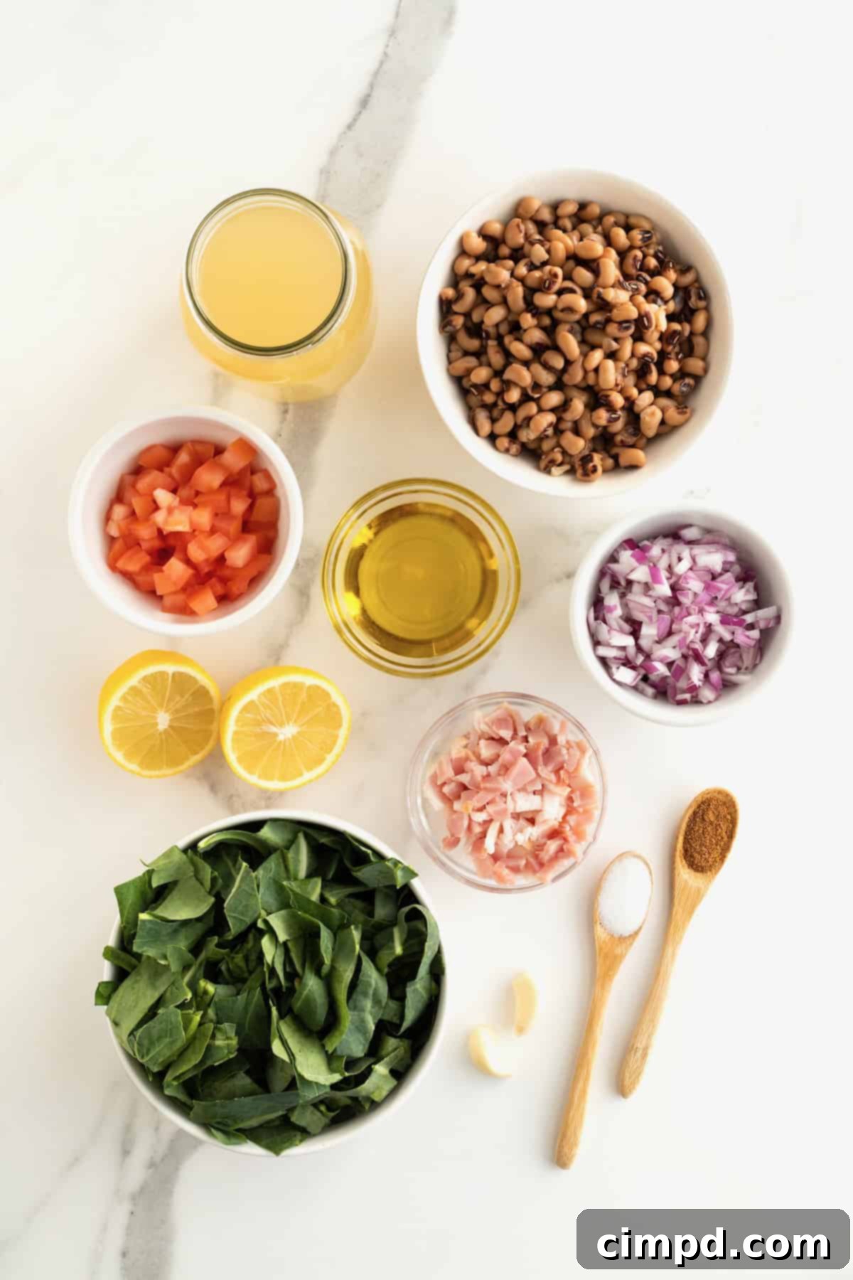 A curated display of all the fresh ingredients for making black eyed peas and collard greens, arranged neatly in small glass dishes on a pristine white marble counter, visually appealing and ready for preparation.