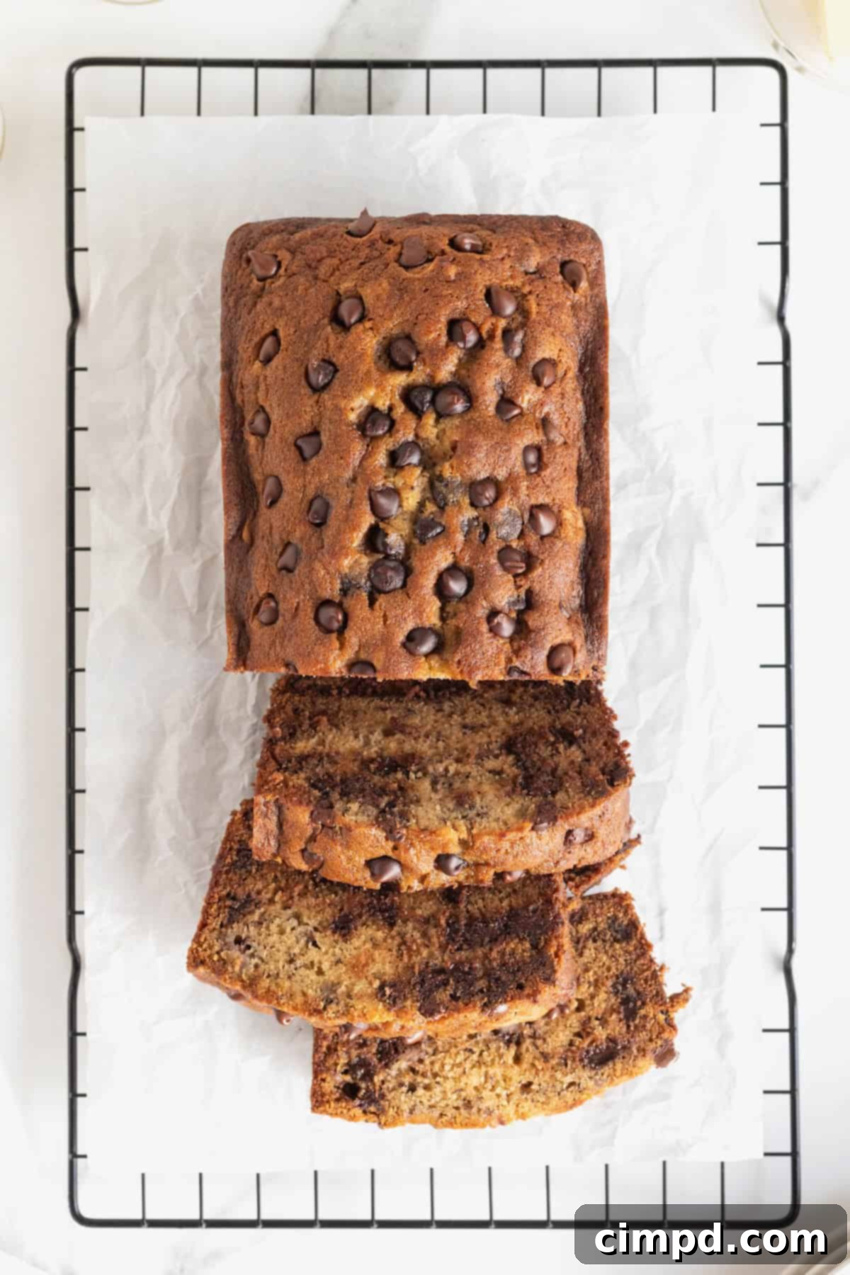 A freshly baked loaf of sliced chocolate chip banana bread resting on a parchment-lined cooling rack, ready to be served.
