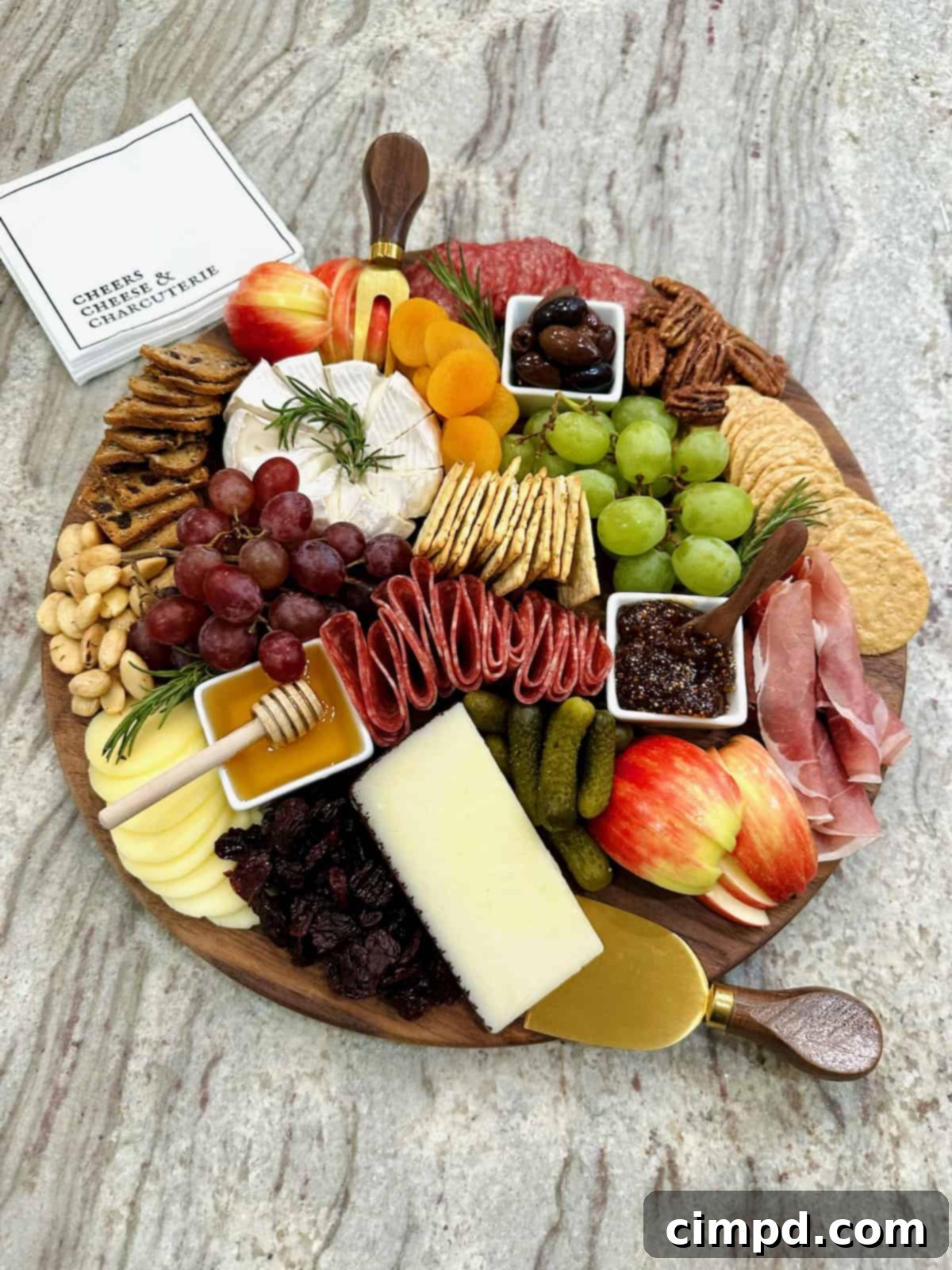 A beautifully composed charcuterie board brimming with a diverse selection of gourmet cheeses, crackers, cured meats, fresh fruits, nuts, and sweet treats, artfully arranged on a gray marble counter, ready for guests.