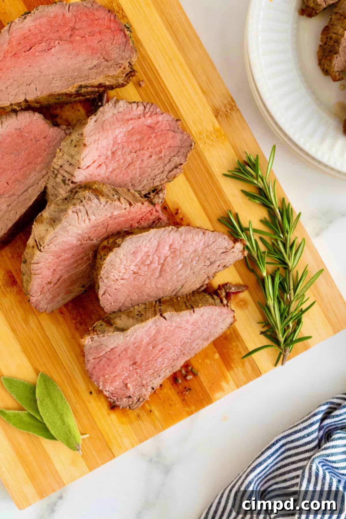 Herb-Crusted Beef Tenderloin 11 Sliced beef tenderloin on a wood cutting board.