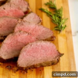 Herb-Crusted Beef Tenderloin 13 Sliced beef tenderloin on a wood cutting board.