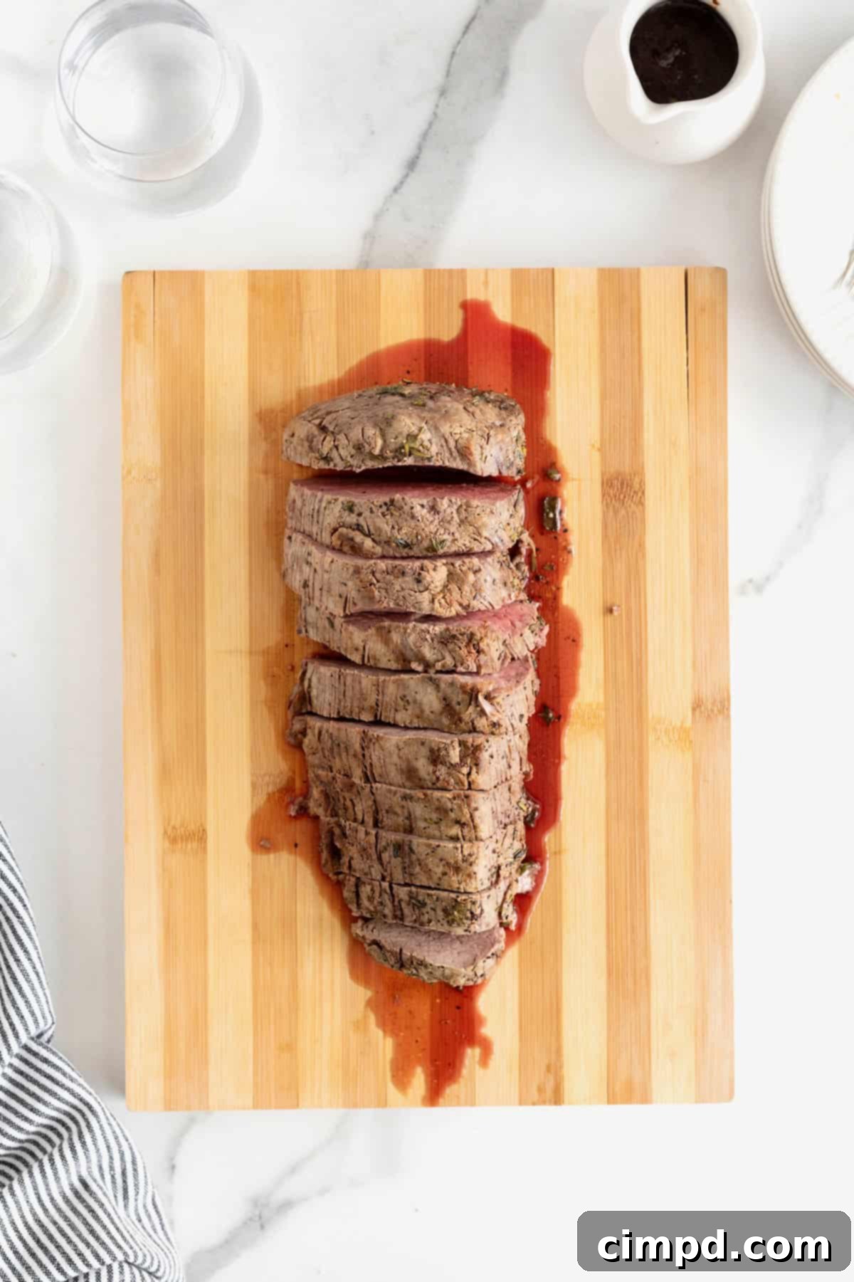 Herb-Crusted Beef Tenderloin 10 Roasted beef tenderloin cut into 1-inch thick pieces on a wood cutting board.