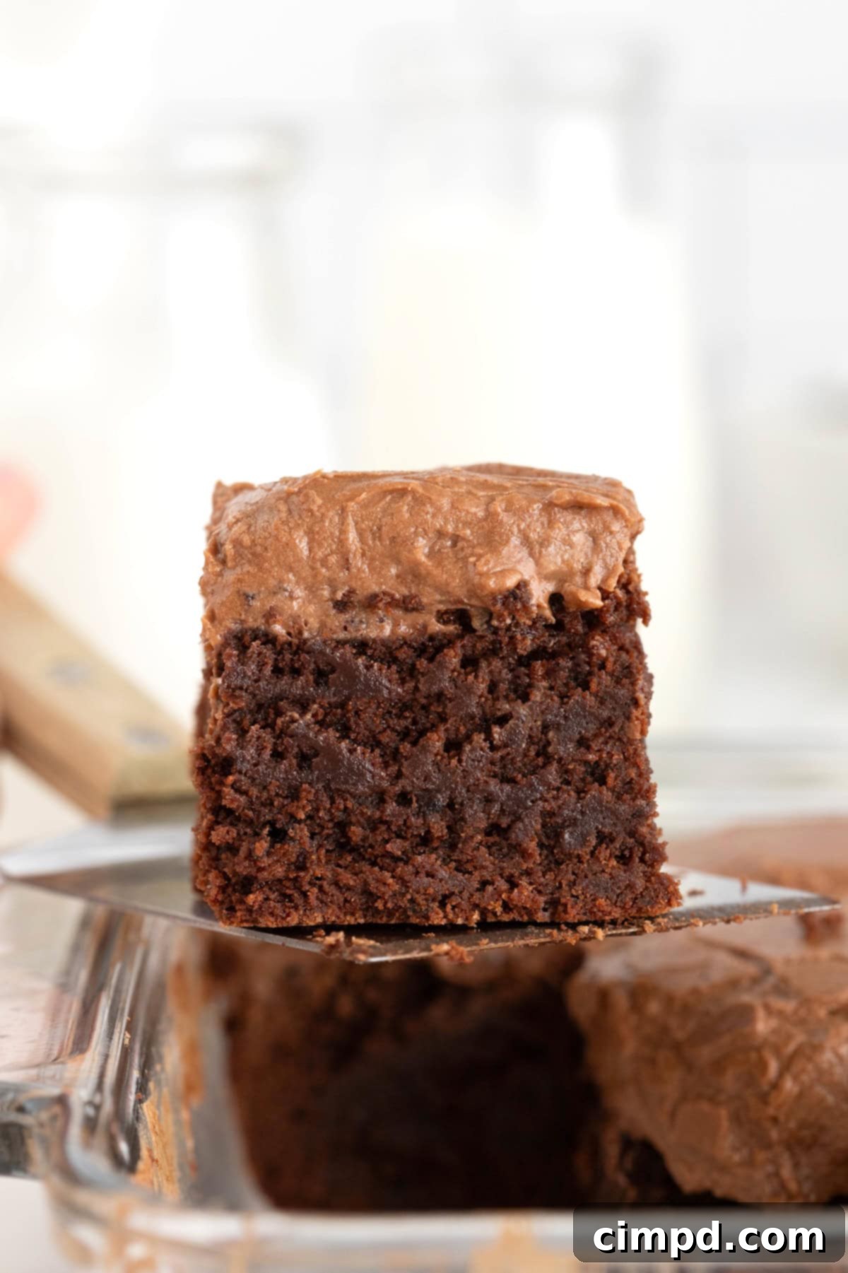 Mocha Velvet Brownies 2 An espresso brownie with frosting being lifted from a baking dish on a wooden handled spatula.