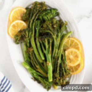 A white oval serving platter of broccolini and lemon slices.