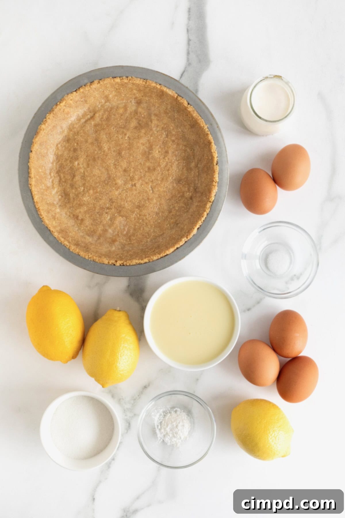 Zesty Meringue Dream 6 A vibrant collection of ingredients laid out on a clean white marble counter, including fresh lemons, eggs, a can of sweetened condensed milk, and other components poised to be transformed into a delicious Lemon Meringue Pie.