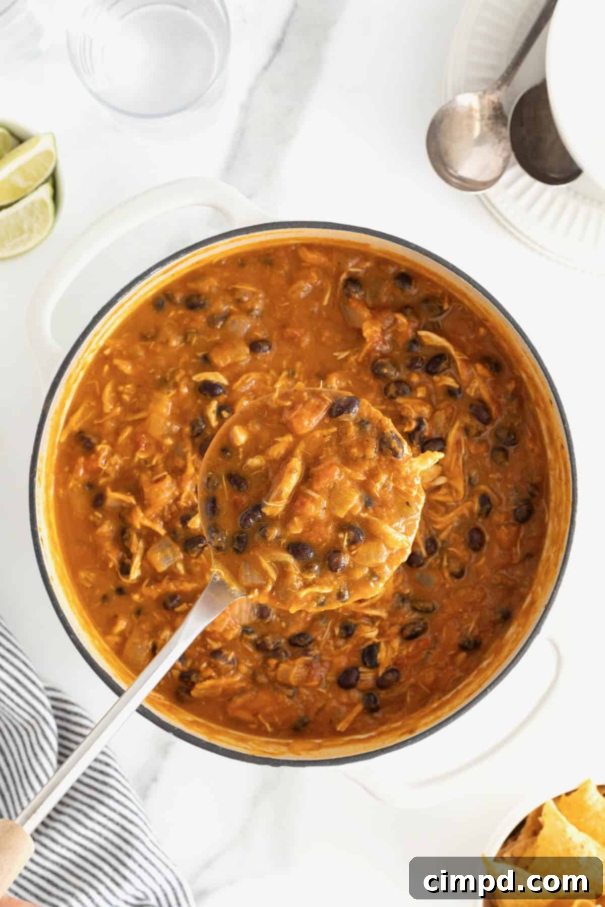 Harvest Pumpkin Chicken Chili 5 A ladle full of chicken pumpkin chili being spooned out of a large white Dutch oven.
