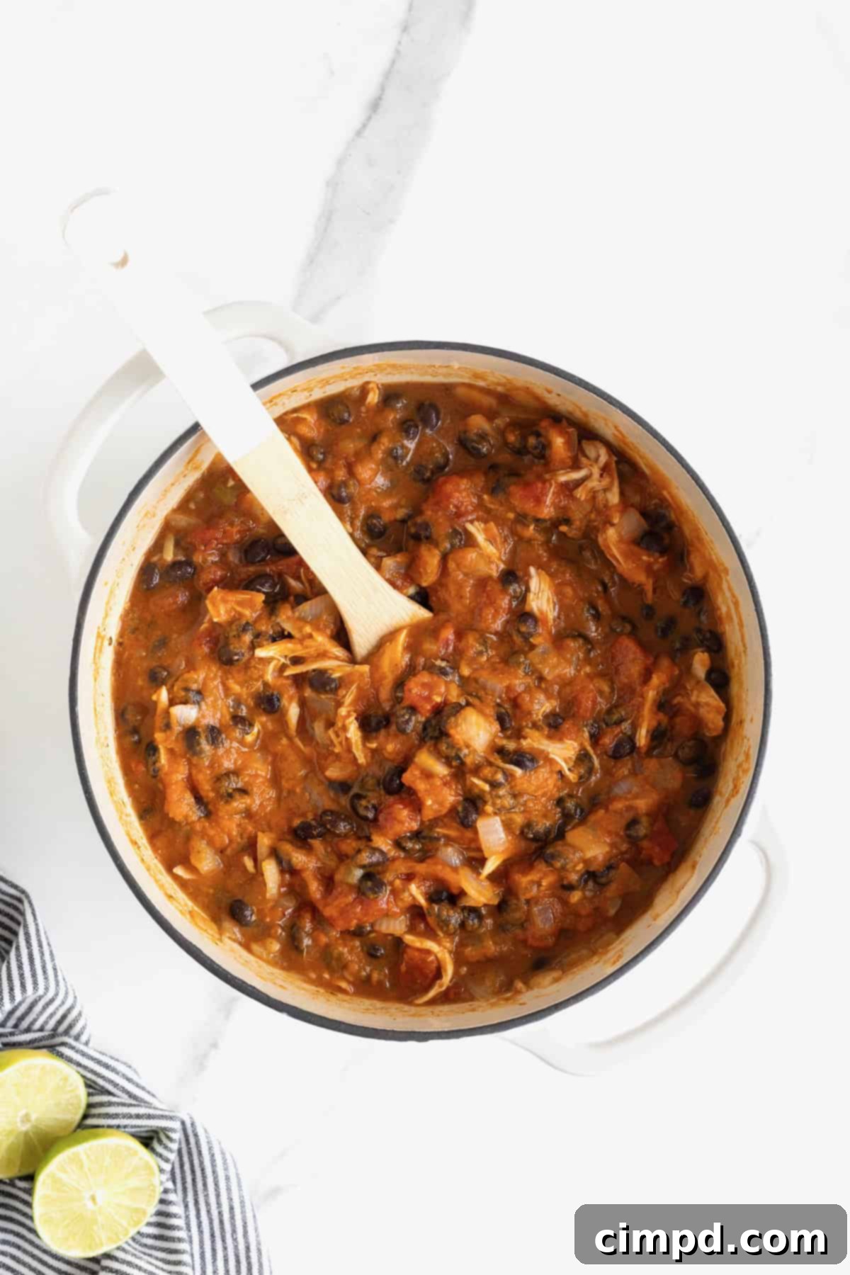 Harvest Pumpkin Chicken Chili 8 A white Dutch oven of chicken pumpkin chili on a white marble counter.