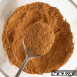 Make Your Own Pumpkin Pie Spice 9 A spoonful of pumpkin pie spice over a glass bowl of mixed spices.
