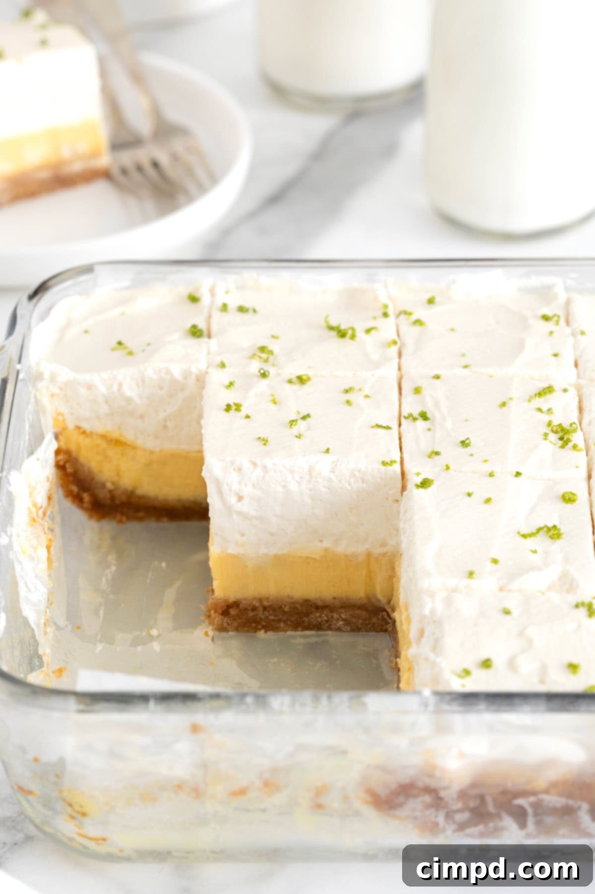A square glass baking dish of key lime pie bars. Three squares are missing from the pan.