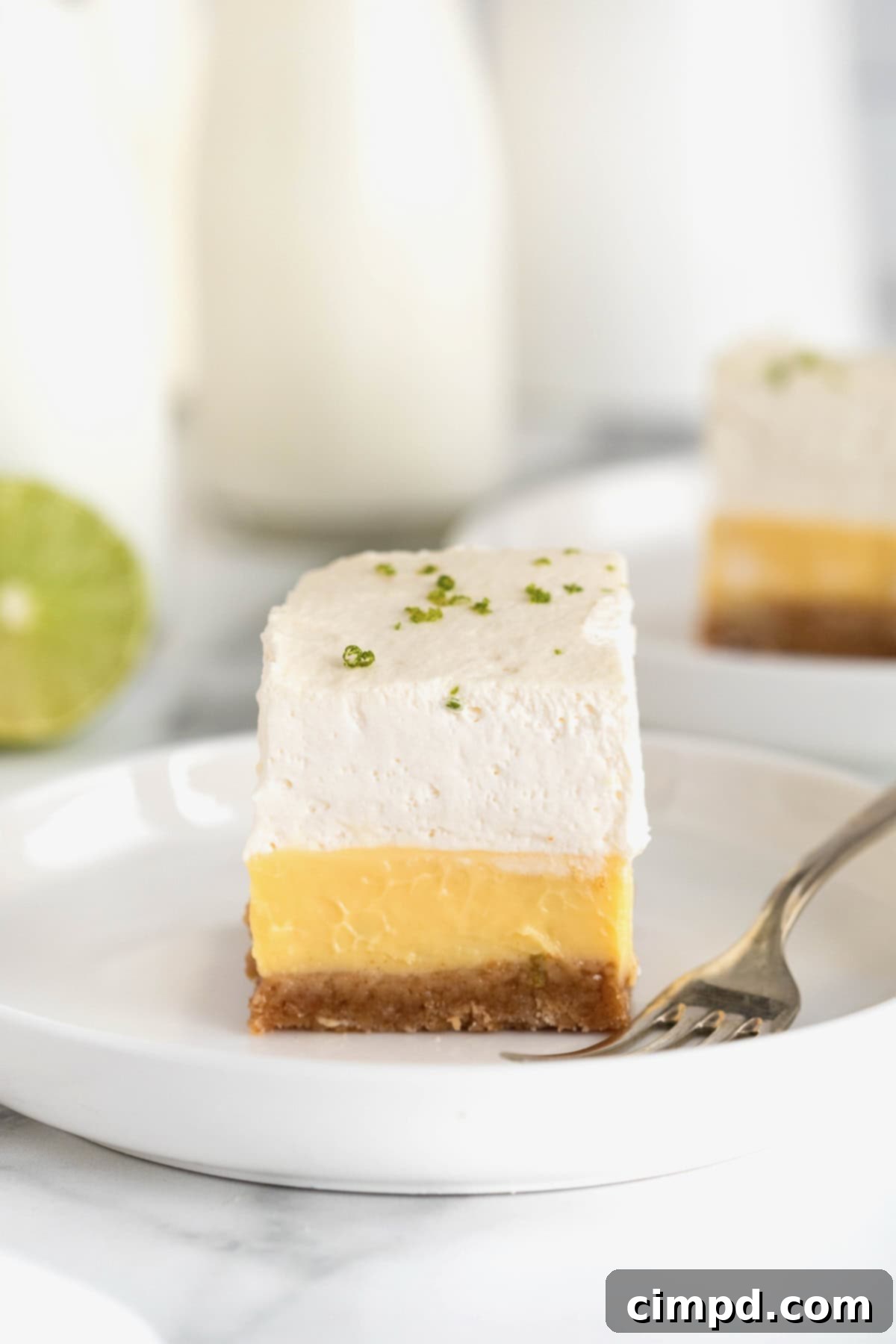 A key lime pie bar on a small white plate with a fork.