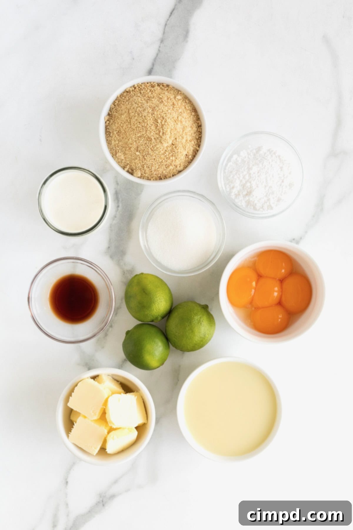 Ingredients to make Key Lime Pie Bars in small white dishes on a white marble counter.