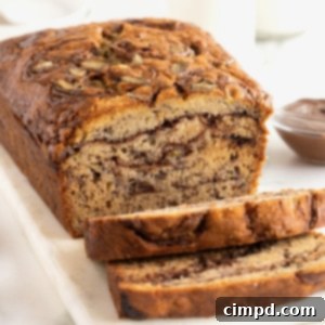 A loaf of Nutella swirled banana bread on a rectangular white serving platter. The bread is sliced, revealing the swirls of Nutella inside.