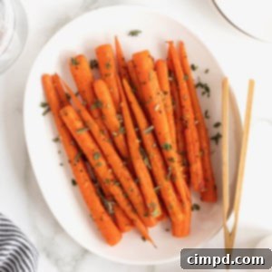 Golden Roasted Carrots 10 An oblong white serving platter of roasted carrots. A pair of wooden tongs rests on the plate.