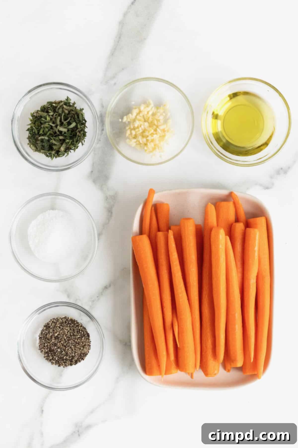 Golden Roasted Carrots 5 A beautifully arranged collection of ingredients for roasted carrots, displayed in elegant glass dishes on a pristine white marble counter.