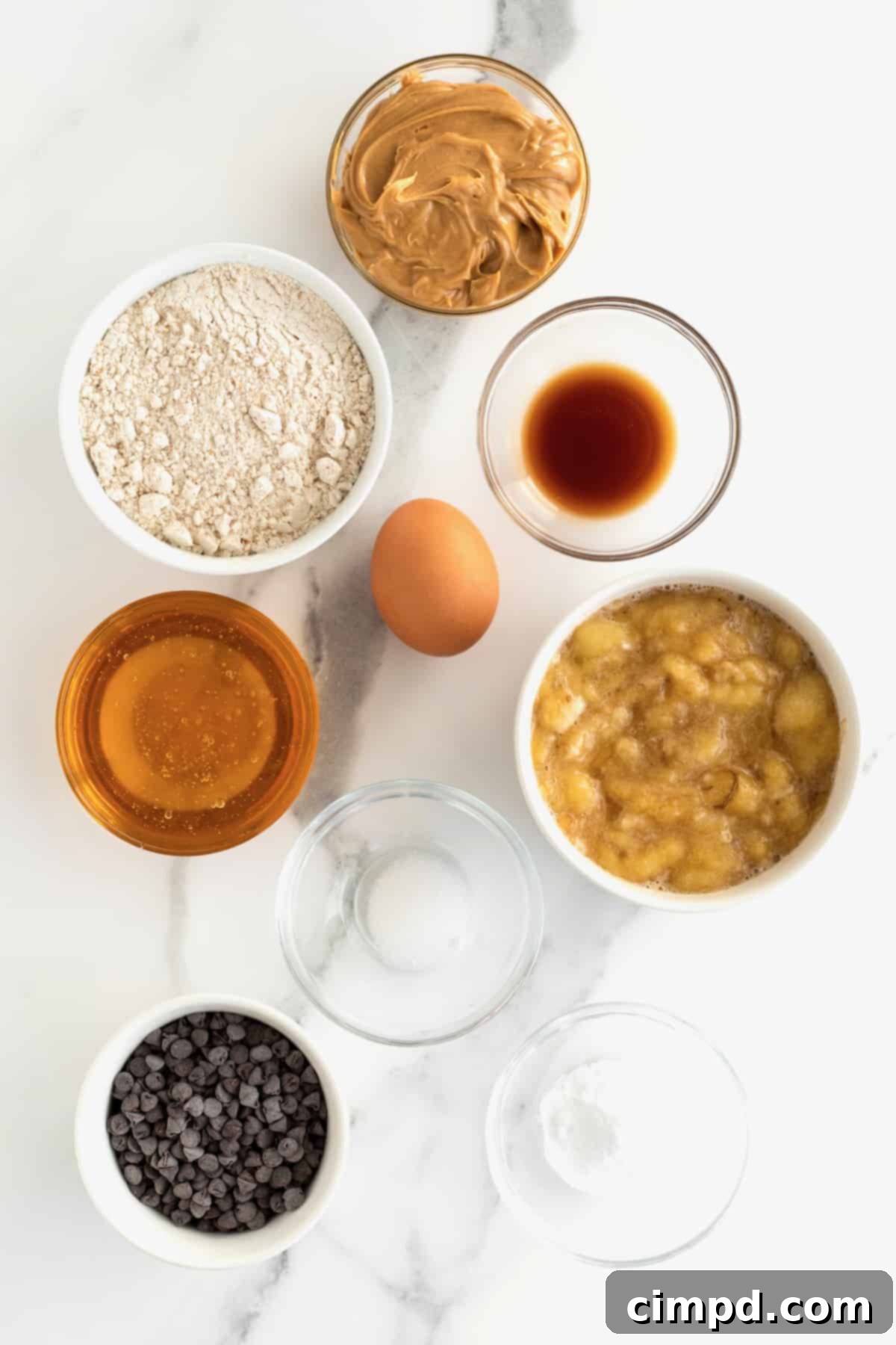 A vibrant display of fresh, wholesome ingredients: ripe bananas, creamy peanut butter, golden honey, and rich mini chocolate chips, all ready to transform into healthy muffins.