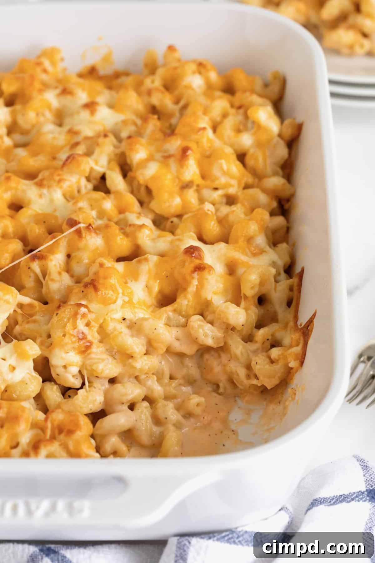 A white ceramic casserole dish of baked macaroni and cheese, golden brown and bubbling.