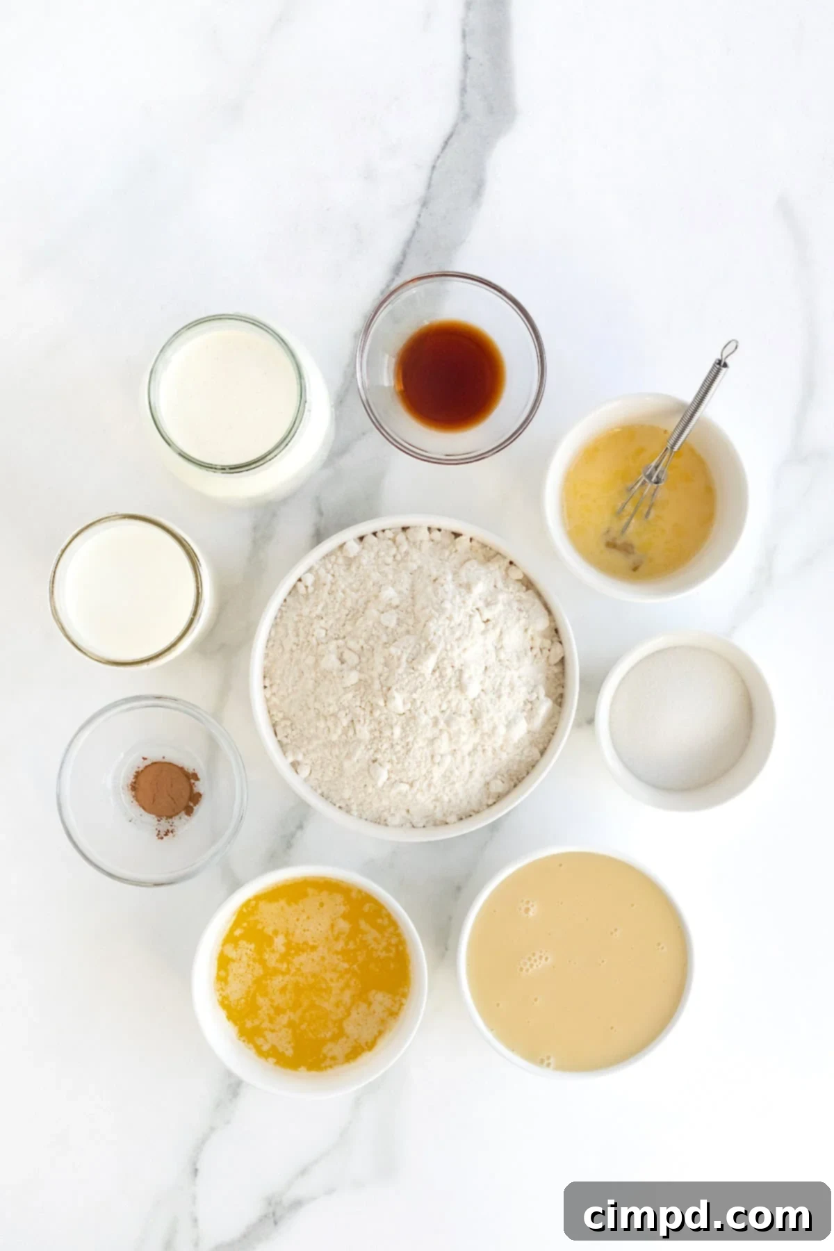 Ingredients to make tres leches cake in small white dishes on a white marble counter.