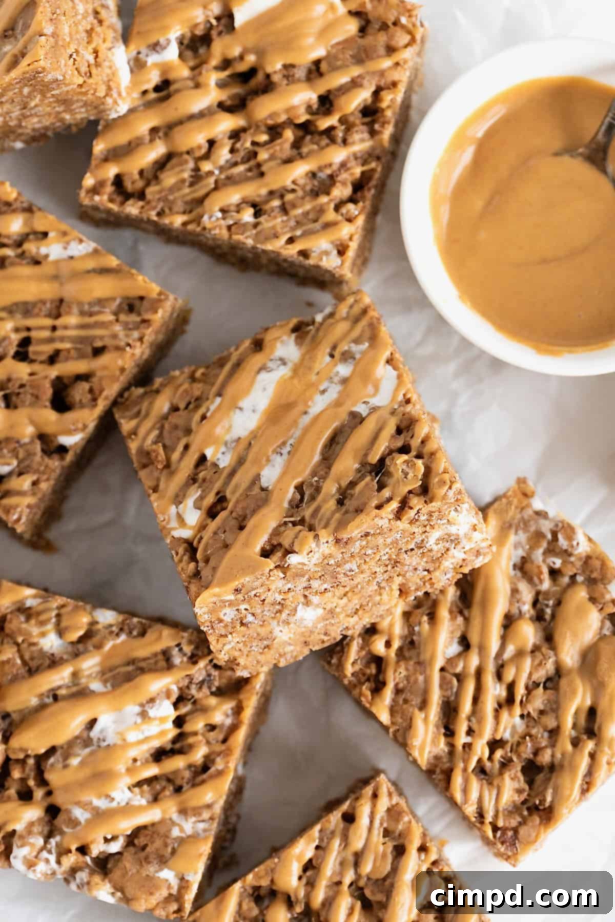 A generous pile of freshly made Chocolate Peanut Butter Rice Krispies Treats, drizzled with extra peanut butter, rests on an elegant white and gray marble counter, ready to be enjoyed.