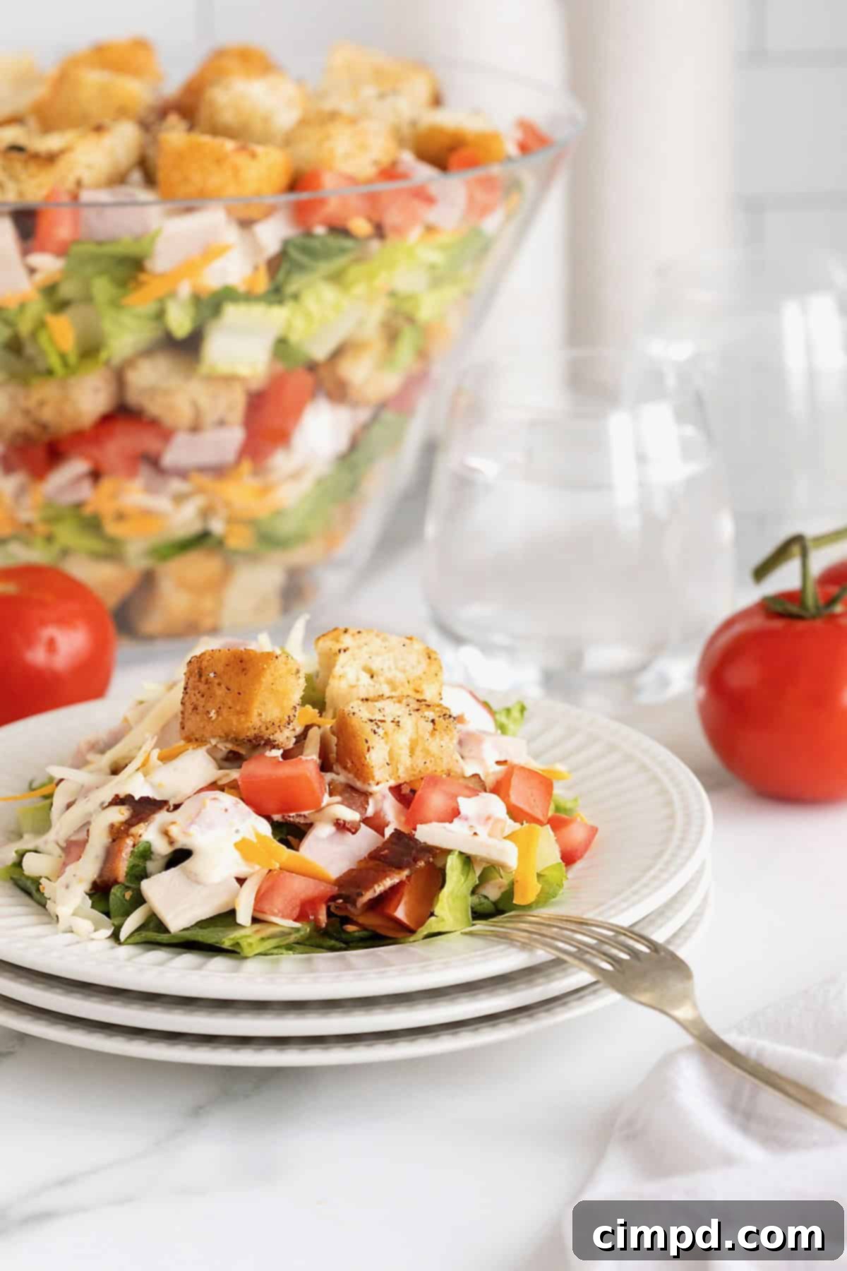 Club Salad Parfait 3 A stack of three white salad plates with a serving of layered club salad topped with croutons.