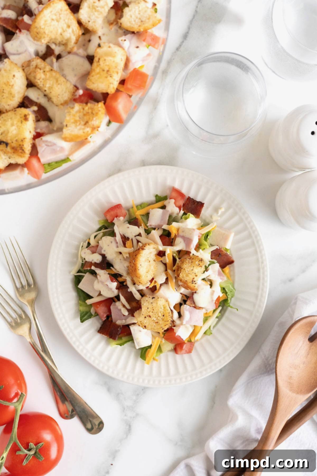 Club Salad Parfait 5 A stack of three white salad plates with a serving of layered club salad topped with croutons.