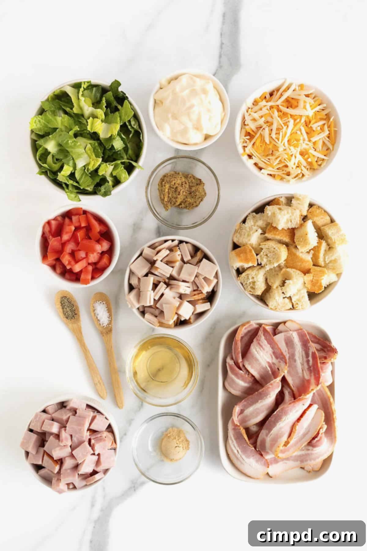 Club Salad Parfait 6 Ingredients to make a layered club salad in small dishes on a white marble counter.