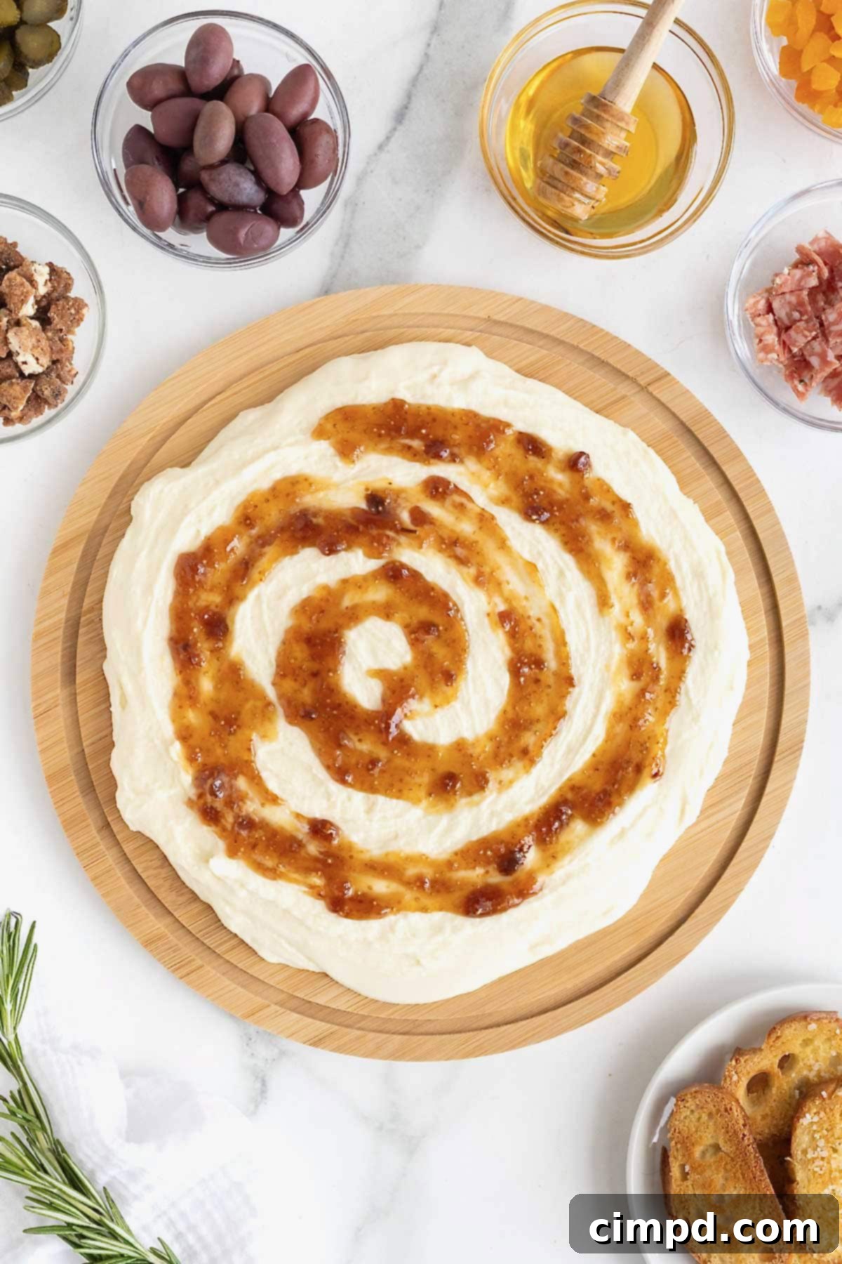 Warm fig jam delicately swirled over a bed of creamy whipped brie on a rustic wooden food board, creating an inviting visual.