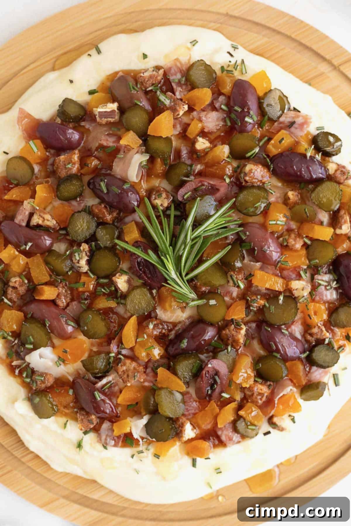 The finished charcuterie dip, a masterpiece of flavors and textures, perfectly garnished on a round wooden board.