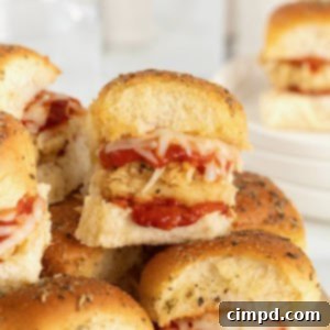 Chicken parmesan sliders on a wooden cutting board on a white marble counter.