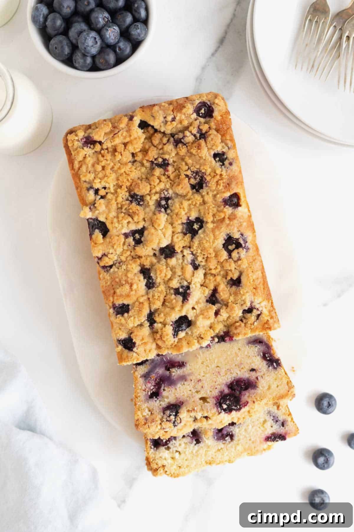 A loaf of lemon blueberry bread studded with blueberries and topped with a streusel on a whim serving platter.