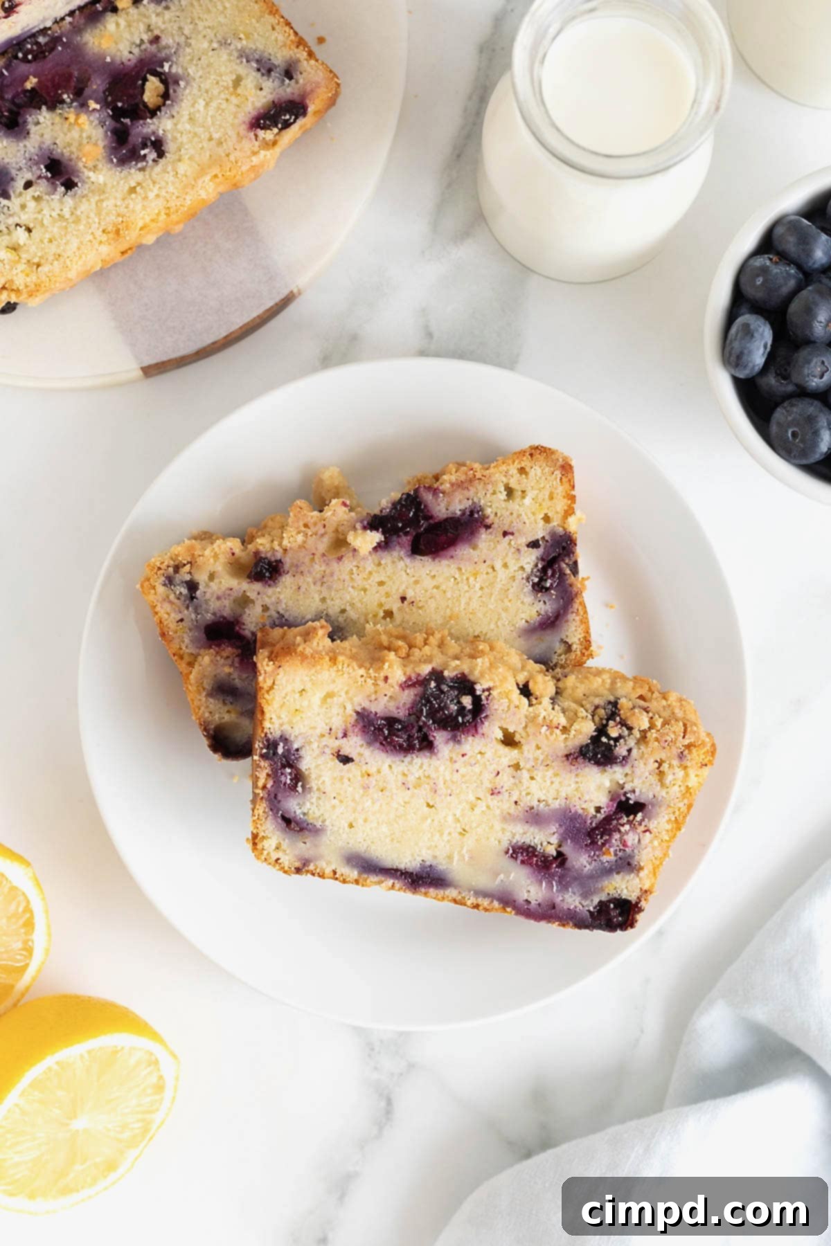 Two slices of lemon blueberry bread on a steak of three small white plates.