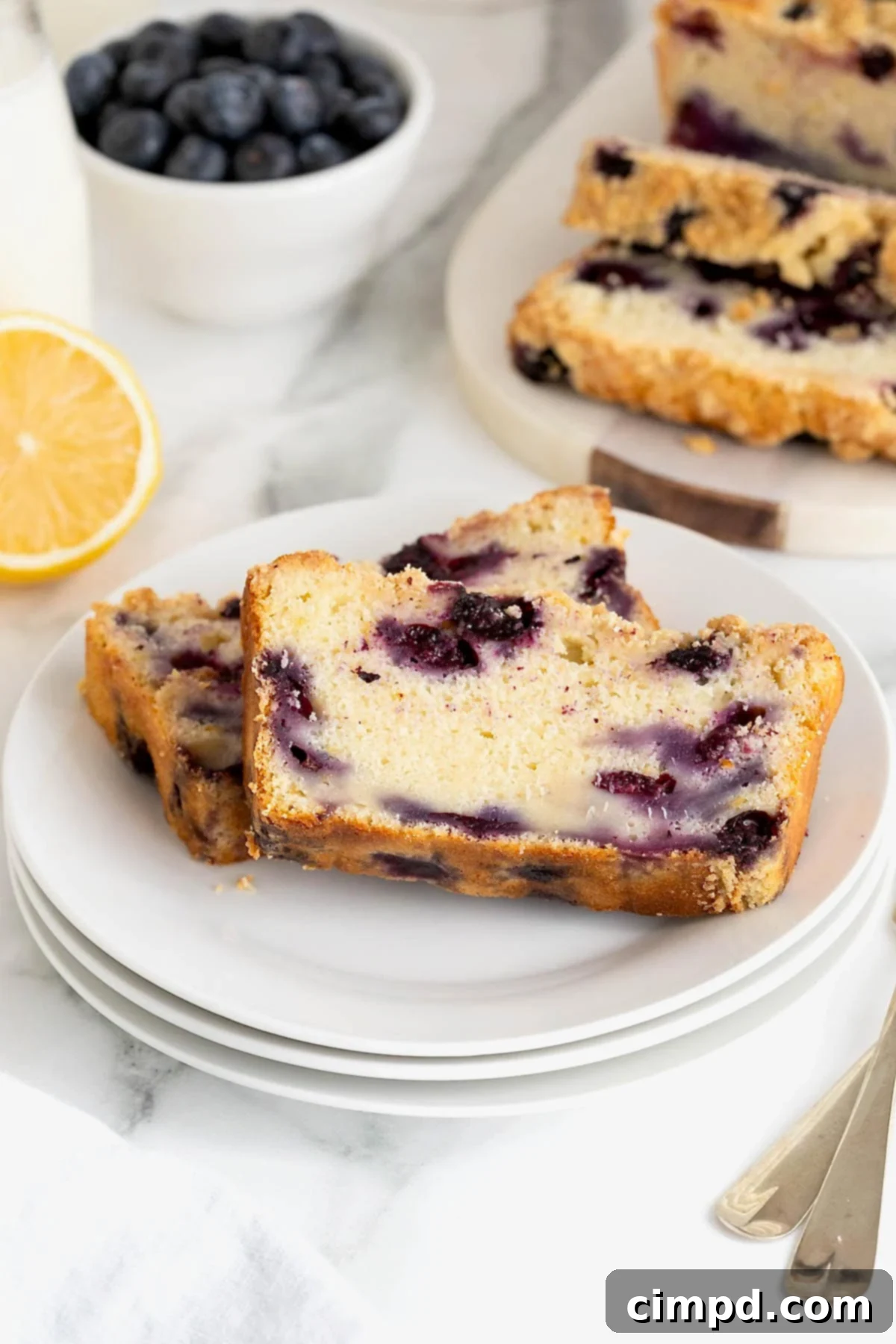 Two slices of lemon blueberry bread on a steak of three small white plates. 