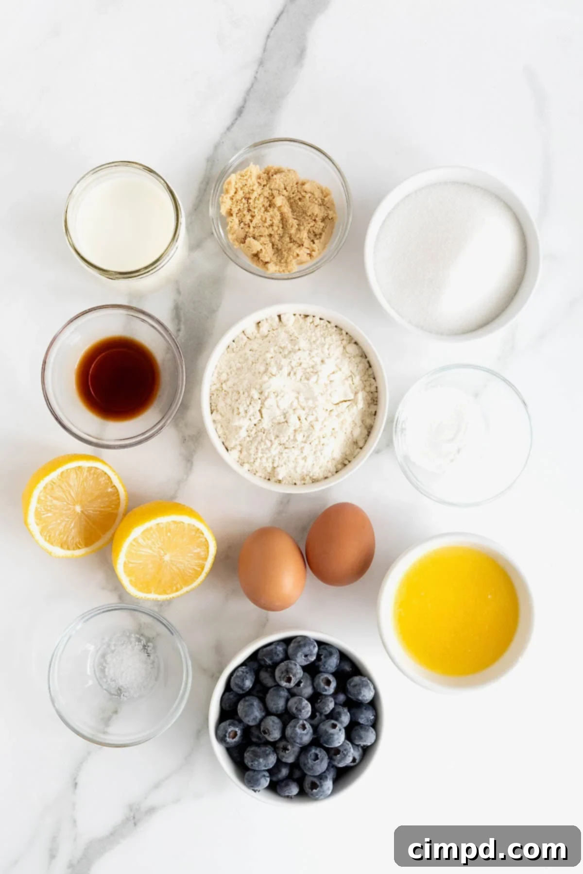 Ingredients to make lemon blueberry bread with streusel in small glass dishes on a white marble counter.