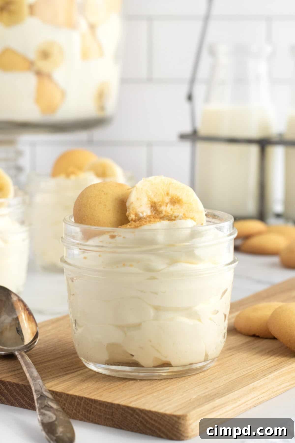 A close-up of The Best Banana Pudding showcasing its luscious layers and inviting texture, with the top garnished with whole and crushed vanilla wafers and fresh banana slices.