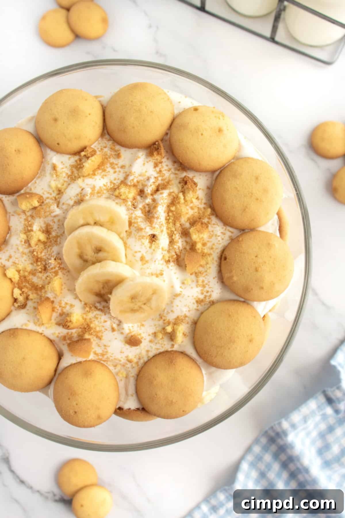 A large container of banana pudding topped with banana slices and vanilla wafers, set on a rustic wooden table, ready to be served at a family gathering.
