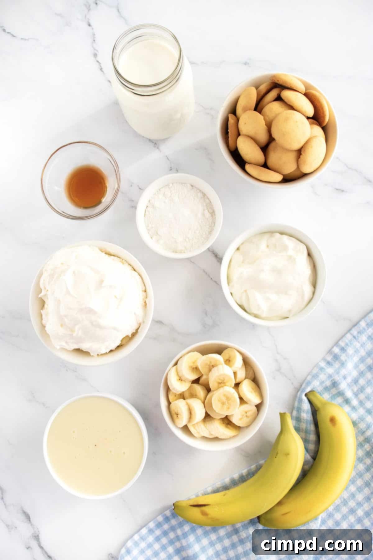 All the fresh ingredients laid out for making The Best Banana Pudding: vanilla wafers, bananas, and a creamy pudding mixture.