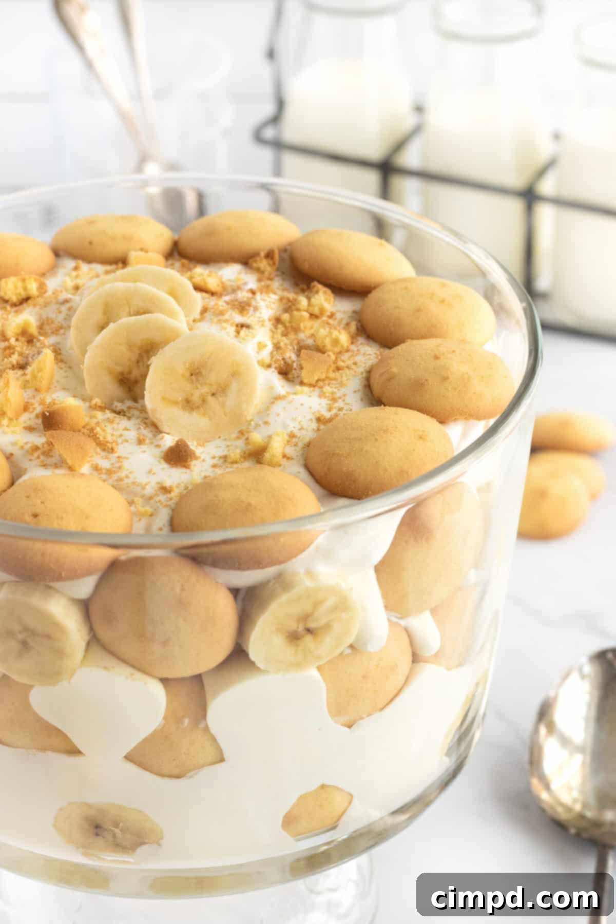 A close-up shot of a single serving of The Best Banana Pudding, showing the creamy texture and layers in a small glass dish, garnished with banana slices.
