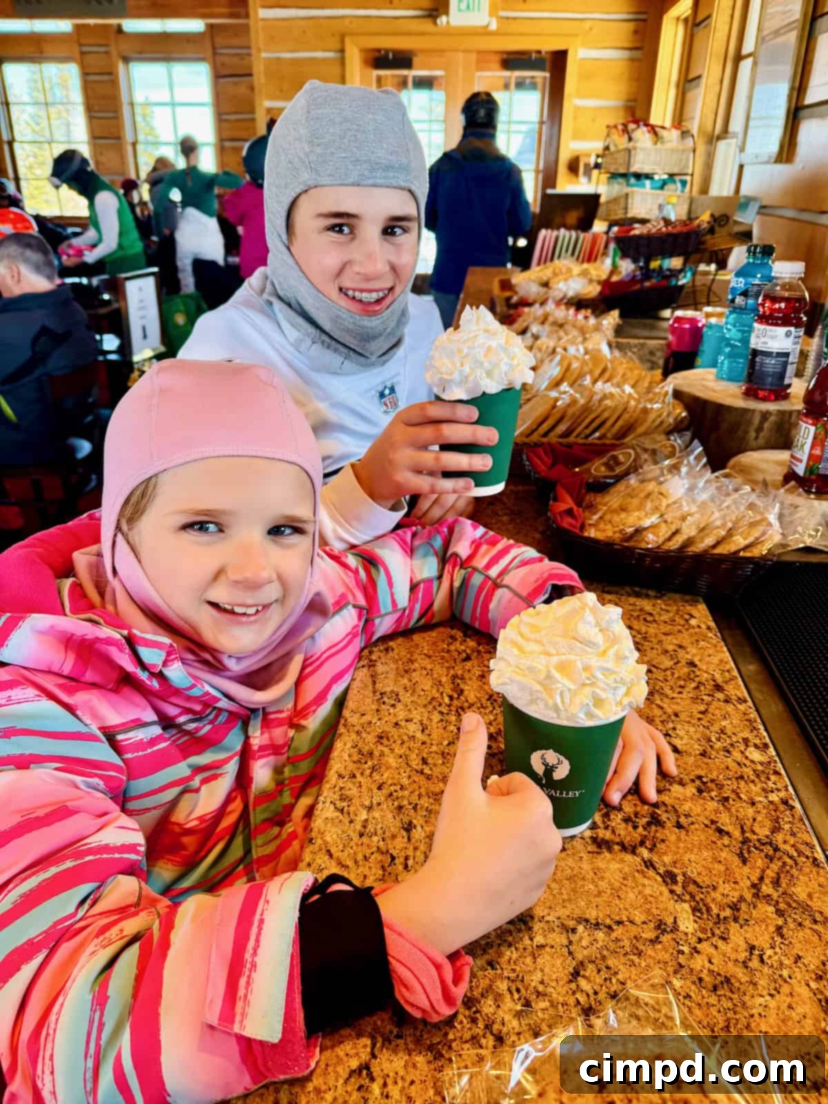 Children delighting in hot chocolate with a mountain of whipped cream inside Cushing's Cabin.