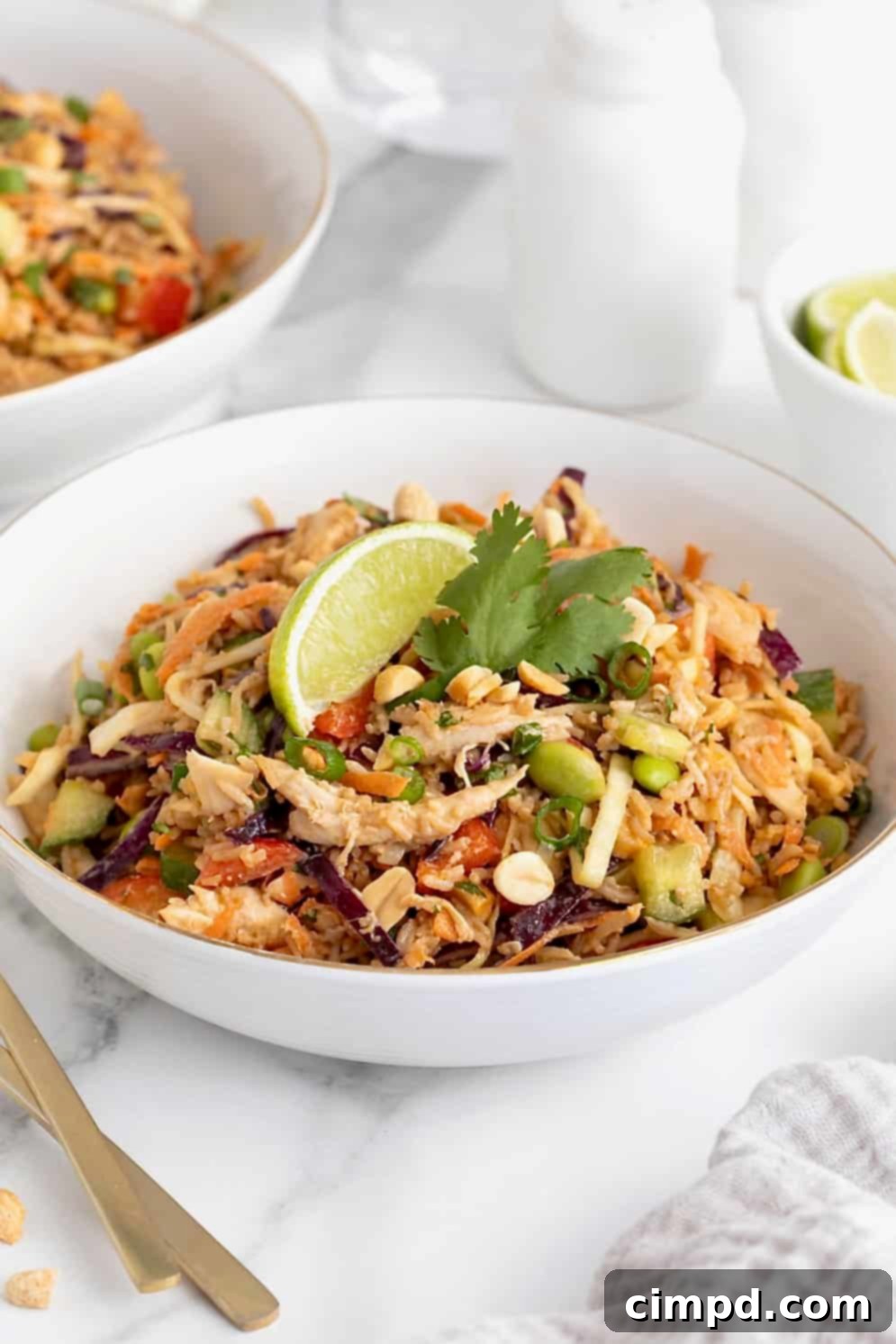 A white bowl filled with crispy rice chicken salad topped with a lime wedge.