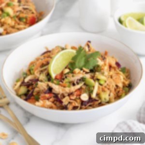 A large white serving bowl of crispy rice salad with two wooden spoons sticking out.
