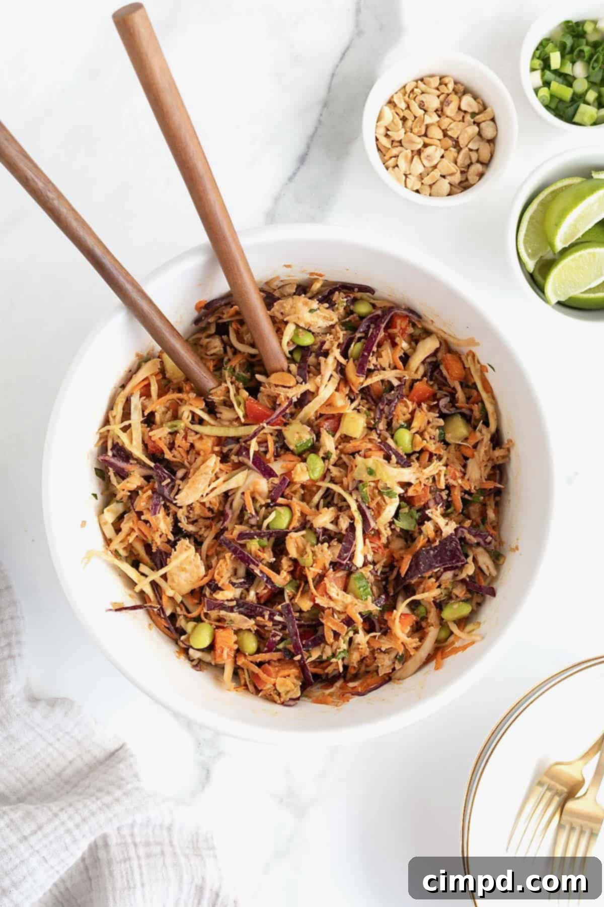 A large white serving bowl of crispy rice salad with two wooden spoons sticking out.