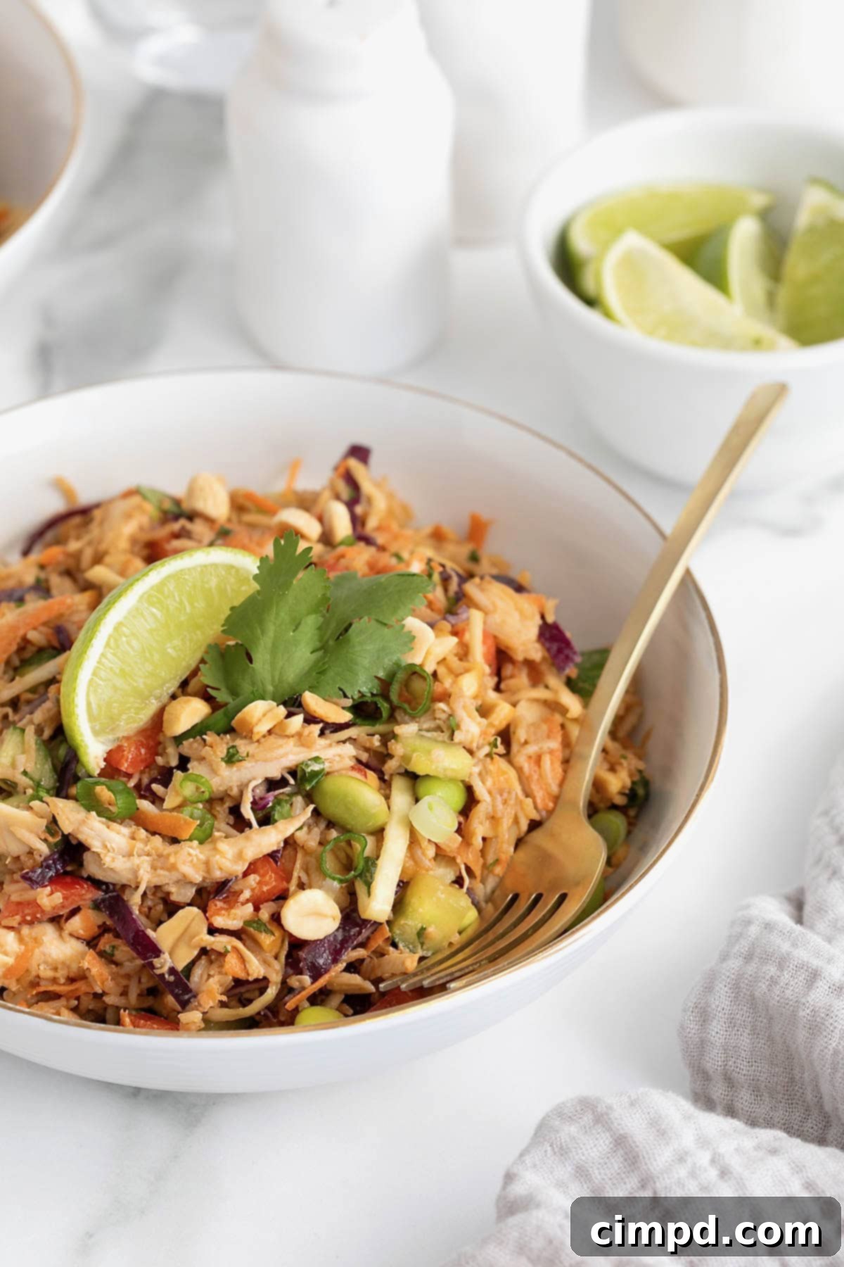 A white bowl filled with crispy rice chicken salad topped with a lime wedge.