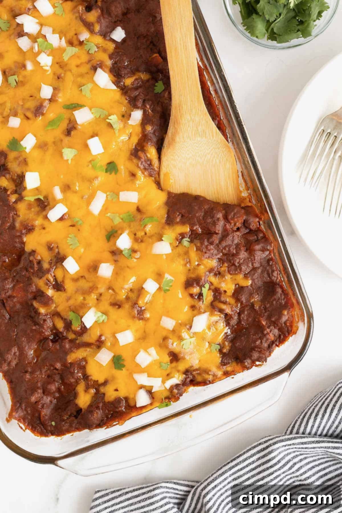 A close-up shot of a pyrex dish filled with hot Chili Con Carne Enchiladas, ready to be served.