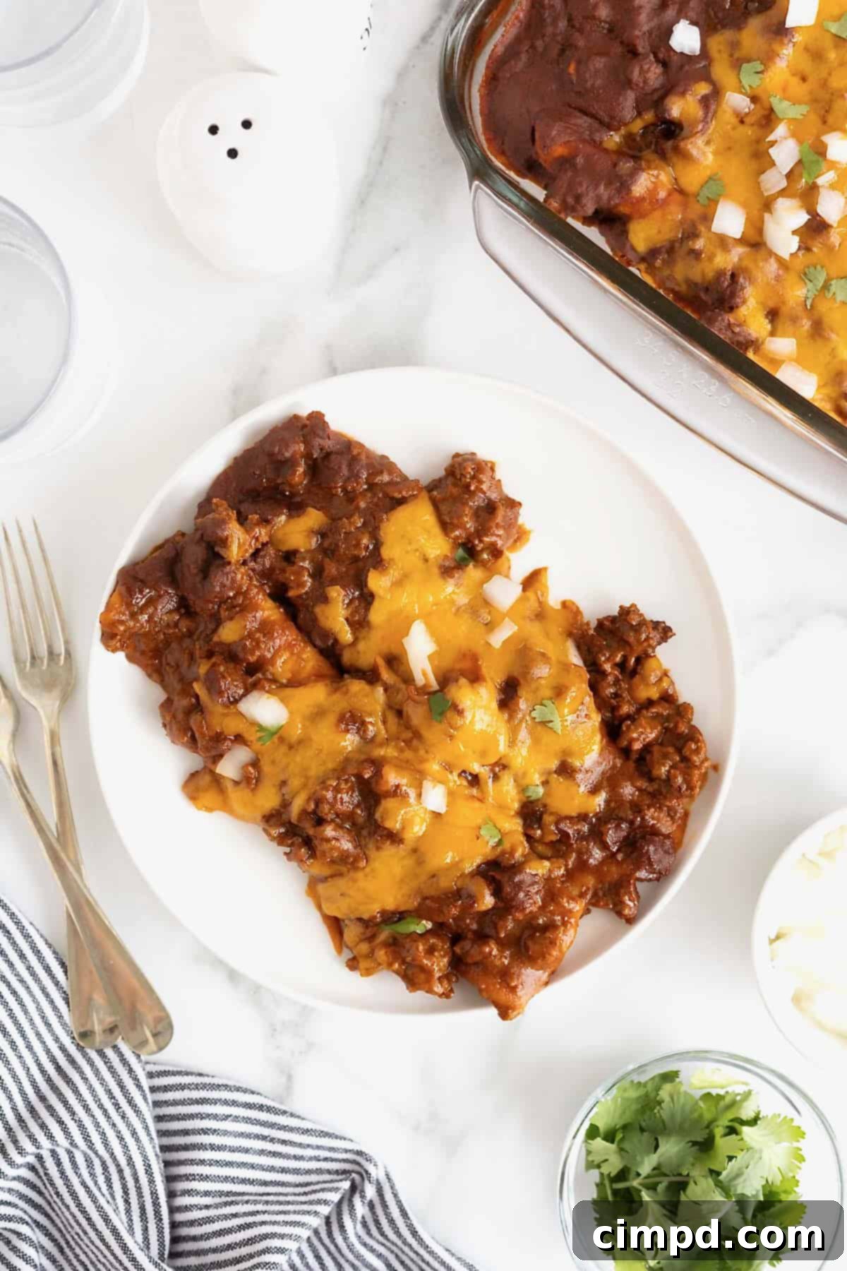 Three perfectly plated Chili Con Carne Enchiladas, artfully stacked on white plates, ready to be enjoyed.