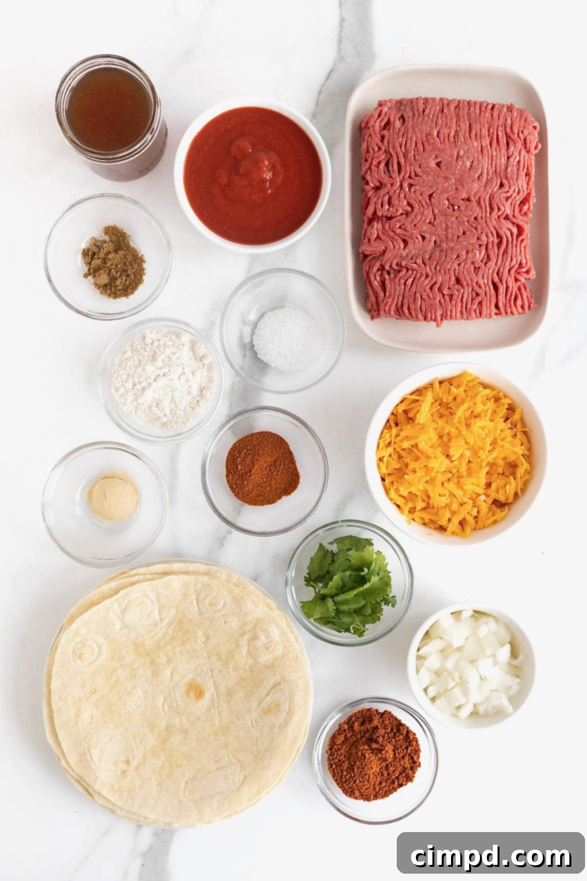 A vibrant flat lay of ingredients for Chili Con Carne Enchiladas, neatly arranged in small glass dishes on a white marble counter.
